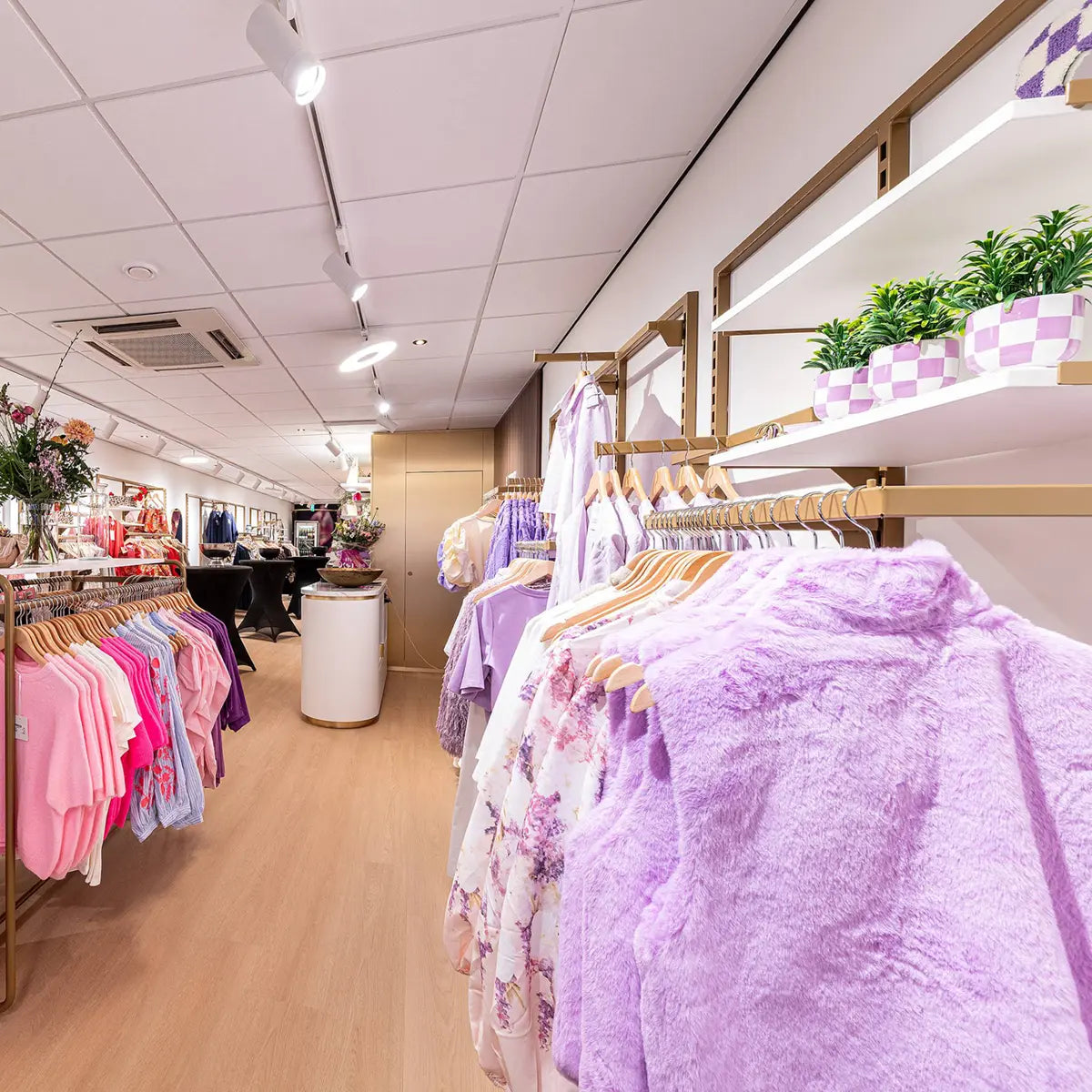Winkelinterieur met diverse kledingmodellen in paars