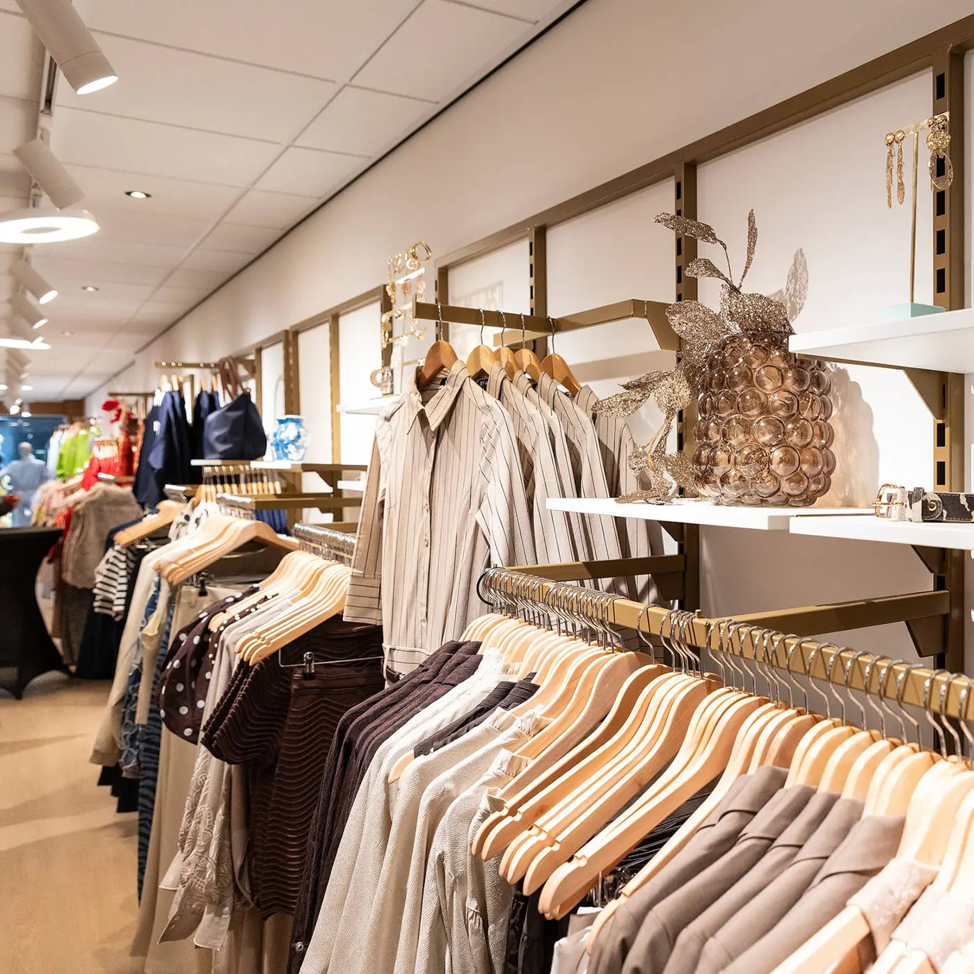 Winkelinterieur met diverse kledingmodellen in bruin