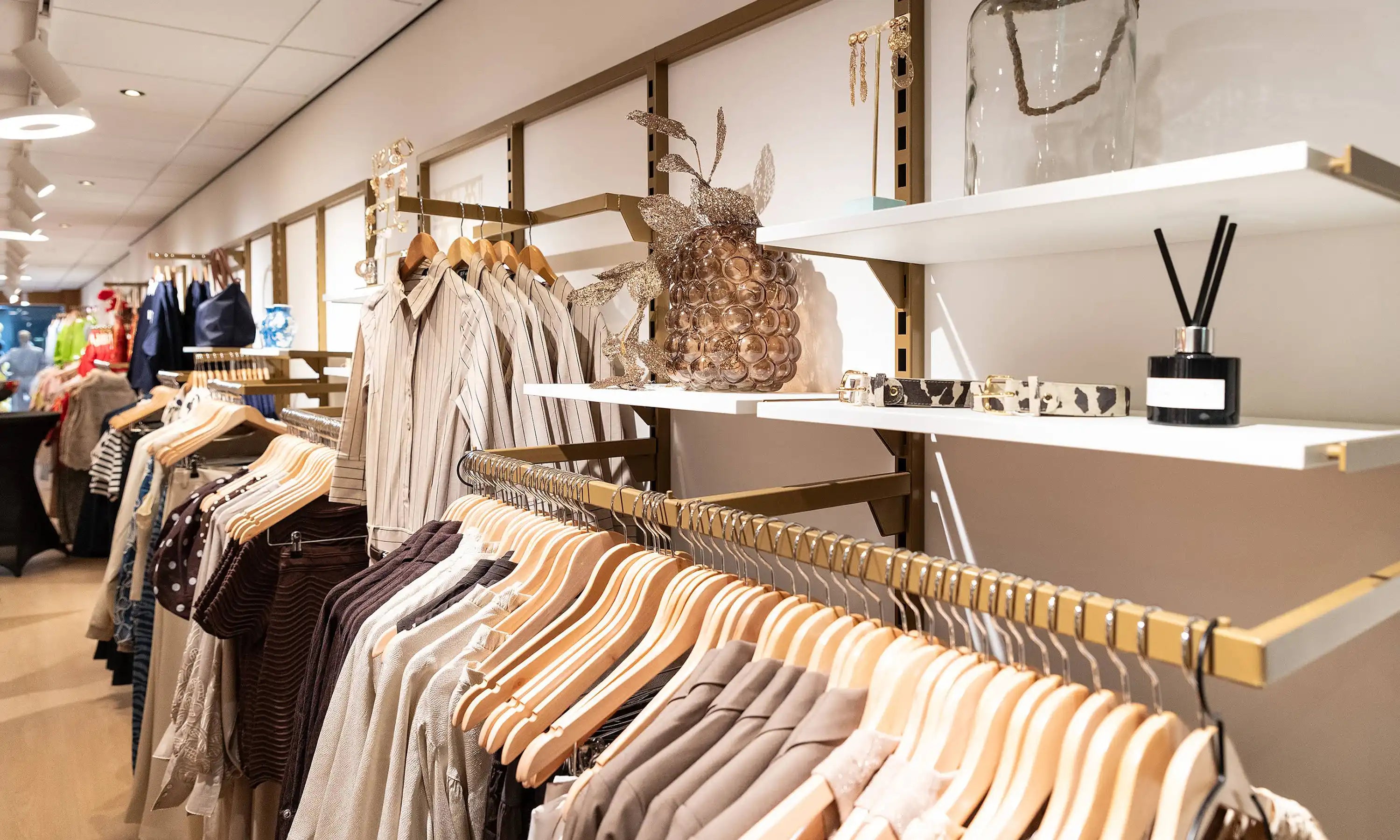 Winkelinterieur met diverse kledingmodellen in bruin